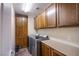 Laundry room featuring dark cabinets, folding table, and stainless-steel washer and dryer at 1557 Blue Sierra Ct, Henderson, NV 89074