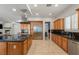 Modern kitchen featuring wood cabinets, granite countertops, stainless steel appliances, and access to the living room at 2285 Villefort Ct, Las Vegas, NV 89117
