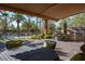 An outdoor kitchen with a grill and dining set under an awning, adjacent to a pool at 2285 Villefort Ct, Las Vegas, NV 89117