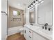 Bright bathroom featuring double vanity with modern fixtures, white cabinets, and a bathtub with tiled walls at 2297 Aria Dr, Henderson, NV 89052
