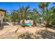 An inviting pool is surrounded by palm trees and a stone patio, perfect for relaxation and enjoying the outdoors at 2770 La Casita Ave, Las Vegas, NV 89120