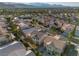 An aerial view showcases a lush residential neighborhood with neatly arranged houses and palm trees against a mountain backdrop at 323 Harpers Ferry Ave, Las Vegas, NV 89148