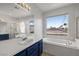 Bright bathroom featuring a soaking tub, vanity, and a large mirror reflecting natural light at 323 Harpers Ferry Ave, Las Vegas, NV 89148