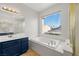 Bathroom featuring a soaking tub, vanity, lighting fixtures and large window providing natural light at 323 Harpers Ferry Ave, Las Vegas, NV 89148