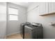 Well-lit laundry room equipped with gray front loading washer and dryer and white cabinets at 323 Harpers Ferry Ave, Las Vegas, NV 89148