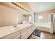 Bright bathroom featuring double sinks, large mirror, bathtub and shower with glass doors at 3624 Snowy Pines St, Las Vegas, NV 89147