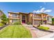 Two-story tan home with a green lawn, brick driveway, and red front door at 3738 Amber Lantern Cir, Las Vegas, NV 89147