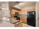 Kitchen featuring wooden cabinets, granite countertops, a black refrigerator and a modern chandelier at 5855 Valley Dr # 2130, North Las Vegas, NV 89031