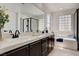 Well-lit bathroom featuring double sinks, glass block window, and bathtub with black trim shower at 6652 Coral Springs Cir, Las Vegas, NV 89108