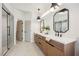 Bright bathroom with double sinks, stylish mirrors, wooden cabinets, and a glass shower at 9308 Pitching Wedge Dr, Las Vegas, NV 89134