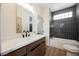 Modern bathroom featuring dark tiled shower/tub, wooden vanity, and sleek finishes at 9308 Pitching Wedge Dr, Las Vegas, NV 89134