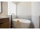 Modern bathroom featuring a standalone tub with black hardware and unique glass block window at 9308 Pitching Wedge Dr, Las Vegas, NV 89134