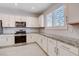 Elegant kitchen with white cabinetry, granite countertops, and stainless steel appliances at 10556 Sariah Skye Ave, Las Vegas, NV 89166
