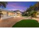 Backyard at dusk with manicured lawn, rock landscaping, and illuminated home, creating a peaceful ambiance at 226 Dalmatian Ln, Las Vegas, NV 89107