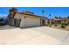 Low angle shot of a single story home with a stucco exterior, large driveway and desert landscaping at 3063 Chapala Dr, Las Vegas, NV 89120