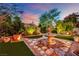 Backyard featuring a stone fountain, manicured lawn, and lush landscaping at sunset at 326 Caneflower Ct, North Las Vegas, NV 89031