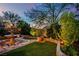 Backyard with a stone fountain, lush greenery, and a peaceful ambiance, illuminated by subtle landscape lighting at 326 Caneflower Ct, North Las Vegas, NV 89031