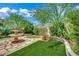 Beautiful backyard with a stone fountain, artificial grass, mature trees and landscaping at 326 Caneflower Ct, North Las Vegas, NV 89031