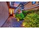 Warm and inviting home entrance with brick walkway, manicured shrubs, and outdoor lighting illuminating the path at 326 Caneflower Ct, North Las Vegas, NV 89031