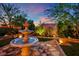 Outdoor space featuring a stunning tiered fountain, lush green landscaping, and warm accent lighting at 326 Caneflower Ct, North Las Vegas, NV 89031