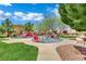 Community playground with colorful equipment, mature trees, and green space for to enjoy at 326 Caneflower Ct, North Las Vegas, NV 89031