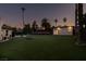 Dusk shot of a backyard with vibrant green lawn, palm trees, and a small building or cabana, suggesting a tranquil outdoor space at 3708 Lorraine Ln, Las Vegas, NV 89120