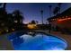 Stunning backyard view with a refreshing pool, lush greenery, and ambient patio lighting at twilight at 3708 Lorraine Ln, Las Vegas, NV 89120