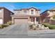 Charming two-story home featuring a tile roof, tan exterior, and a two-car garage, complemented by a landscaped front yard at 4036 W Bird Man Ln, North Las Vegas, NV 89084