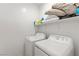 Efficient laundry room featuring a white washer and dryer, plus overhead storage shelves with assorted household items at 4348 Bayley Skye Ave, Las Vegas, NV 89141