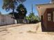 View of the backyard with a chainlink fence and various trees, including palm trees, next to the red brick home at 4950 Burnham Ave, Las Vegas, NV 89119