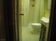 A compact bathroom features a shower, toilet, sink, and storage, with a tiled floor and yellow walls at 4950 Burnham Ave, Las Vegas, NV 89119