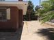 Back exterior view of the brick home, with a sandy yard partially shaded by a mature palm tree at 4950 Burnham Ave, Las Vegas, NV 89119