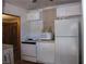 A compact kitchen features white appliances, cabinets, and a microwave with a simple tiled backsplash at 4950 Burnham Ave, Las Vegas, NV 89119