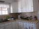 A traditional kitchen features white cabinets, tiled countertops, a sink, and tile backsplash with floral accents at 4950 Burnham Ave, Las Vegas, NV 89119
