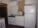 A compact kitchen features white appliances, cabinets, and a microwave with a simple tiled backsplash at 4950 Burnham Ave, Las Vegas, NV 89119