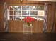 A cozy living room features wood paneling, large windows with curtains, and a small table with flowers at 4950 Burnham Ave, Las Vegas, NV 89119