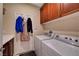 Laundry room includes a washer, dryer, overhead cabinets and hanging space for clothing at 5916 Sorto Lago St, North Las Vegas, NV 89081