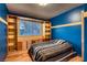 A blue bedroom featuring hardwood flooring, window, storage shelves, and a striped comforter at 6213 Fairwood Ave, Las Vegas, NV 89107