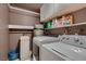 Functional laundry area with white washer and dryer, shelving, and neutral color scheme at 6213 Fairwood Ave, Las Vegas, NV 89107