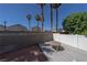 Backyard with a wood deck, a concrete block wall, white fencing, and tall palm trees at 6459 Rusticated Stone Ave # 103, Henderson, NV 89011