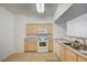 Bright kitchen features light wood cabinetry, a modern white range and microwave, and tile flooring at 6955 N Durango Dr # 1093, Las Vegas, NV 89149