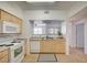 Well-lit kitchen featuring appliances, light wood cabinets, and a pass-through to the living area at 6955 N Durango Dr # 1093, Las Vegas, NV 89149