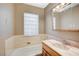 Bathroom featuring glass-block window, single vanity with marble countertop, and bathtub at 819 Sandsprings St, Henderson, NV 89011