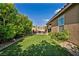 Serene backyard with artificial turf, mature trees, and a covered patio with comfortable outdoor furniture and fire pit at 8346 Vinamala Ave, Las Vegas, NV 89149
