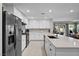 Bright kitchen features white cabinetry, stainless steel appliances, and an island with seating overlooking the backyard at 8346 Vinamala Ave, Las Vegas, NV 89149