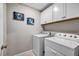 Bright laundry room featuring a white washer and dryer, upper cabinets, and charming wall art at 8346 Vinamala Ave, Las Vegas, NV 89149