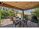 Inviting covered patio with a dining set, lush greenery, and a grill, perfect for outdoor entertaining at 8346 Vinamala Ave, Las Vegas, NV 89149