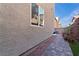 Side view of house with textured wall, outdoor walkway, plants, and a glimpse of the backyard at 10733 Red Badge Ave, Las Vegas, NV 89166