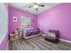 Vibrant purple bedroom with wood floors, ample natural light, cozy furnishings, and ample storage solutions at 10733 Red Badge Ave, Las Vegas, NV 89166