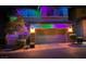 Two story home with a two car garage adorned with color changing holiday lights on a dark evening at 10733 Red Badge Ave, Las Vegas, NV 89166